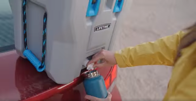 Still from a campaign video of a person filling a water bottle from a Lifetime cooler's drain spout